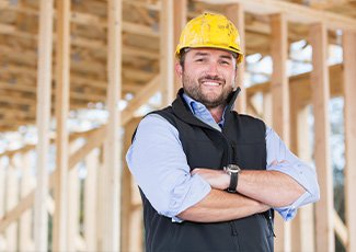 Residential builder on a project site, framed home in the background