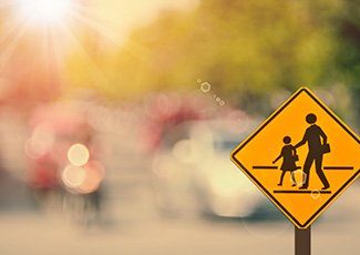 Crossing sign in front of sunny glare