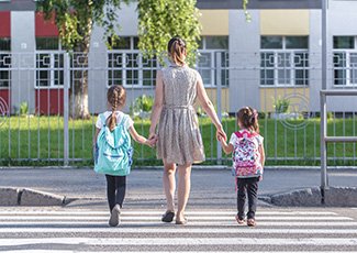 Mom and two children using crosswalk on the way to school