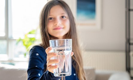 Young girl holding up a glass of drinking water