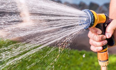 Close up of person using a hose to water their lawn/garden