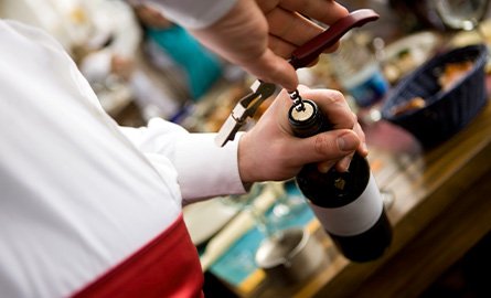 Photo of bartender at private event, opening a bottle of wine