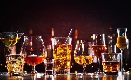 Several alcoholic beverages lined up along a bar counter
