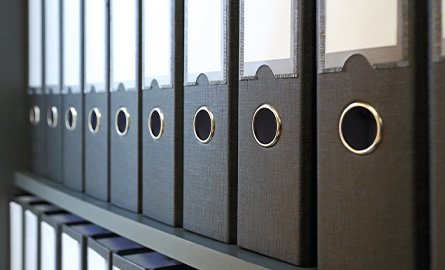 A row of black binders on a shelf