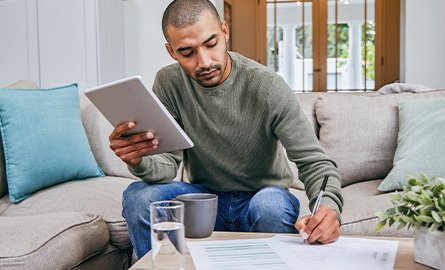 Person filling out paperwork while seated on his couch.