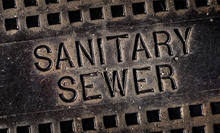 Sanitary sewer man hole cover iron lid reading "Sanitary Sewer"