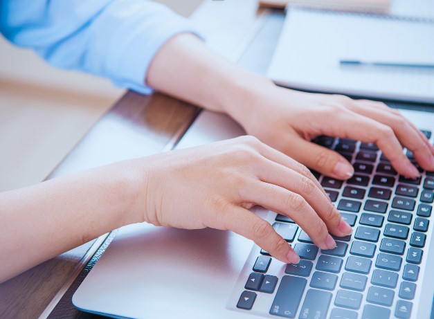 Hands typing on a computer keyboard.
