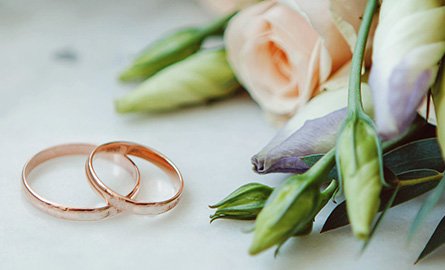 two wedding bands next to a bouquet of flowers