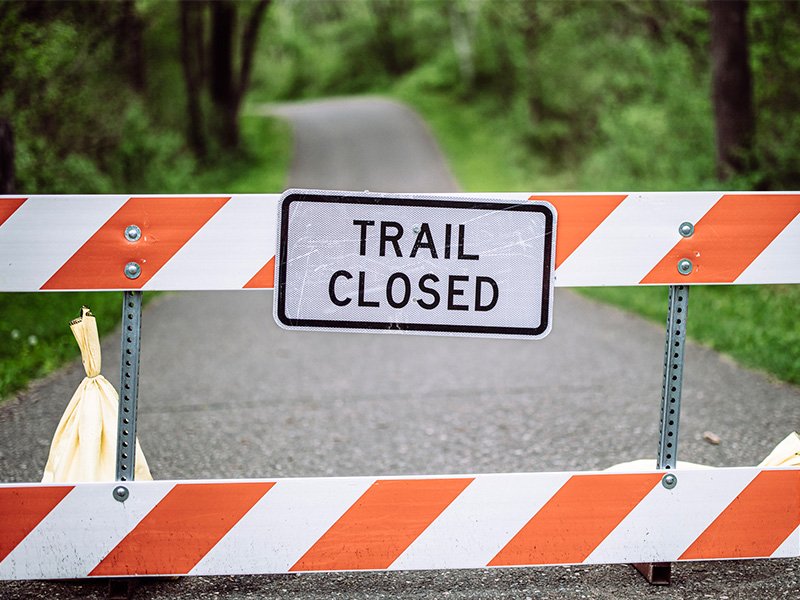 Forest trail blocked off with barracade and trail closed sign