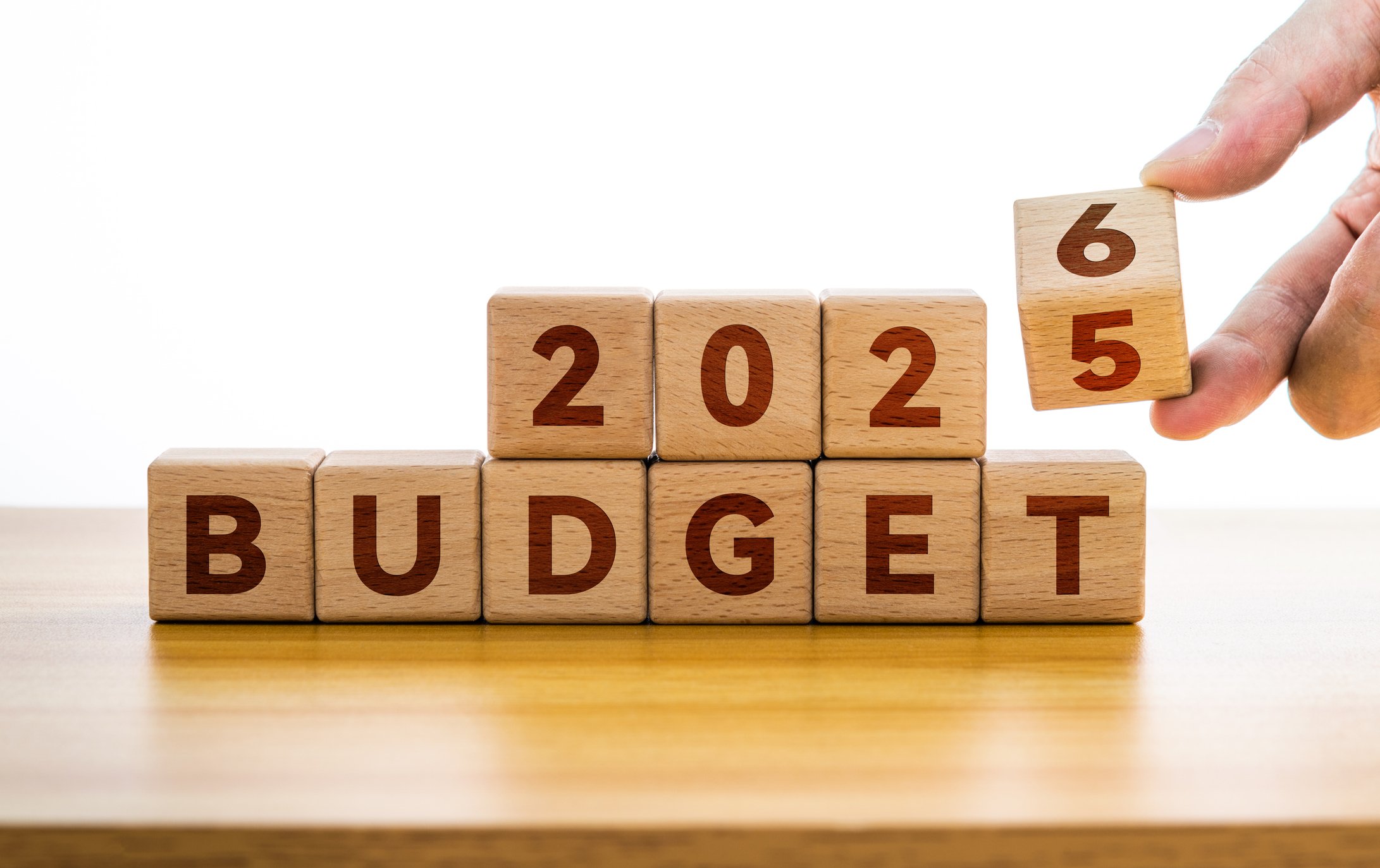 Hand flips wooden cube and changes inscription BUDGET 2025 to BUDGET 2026