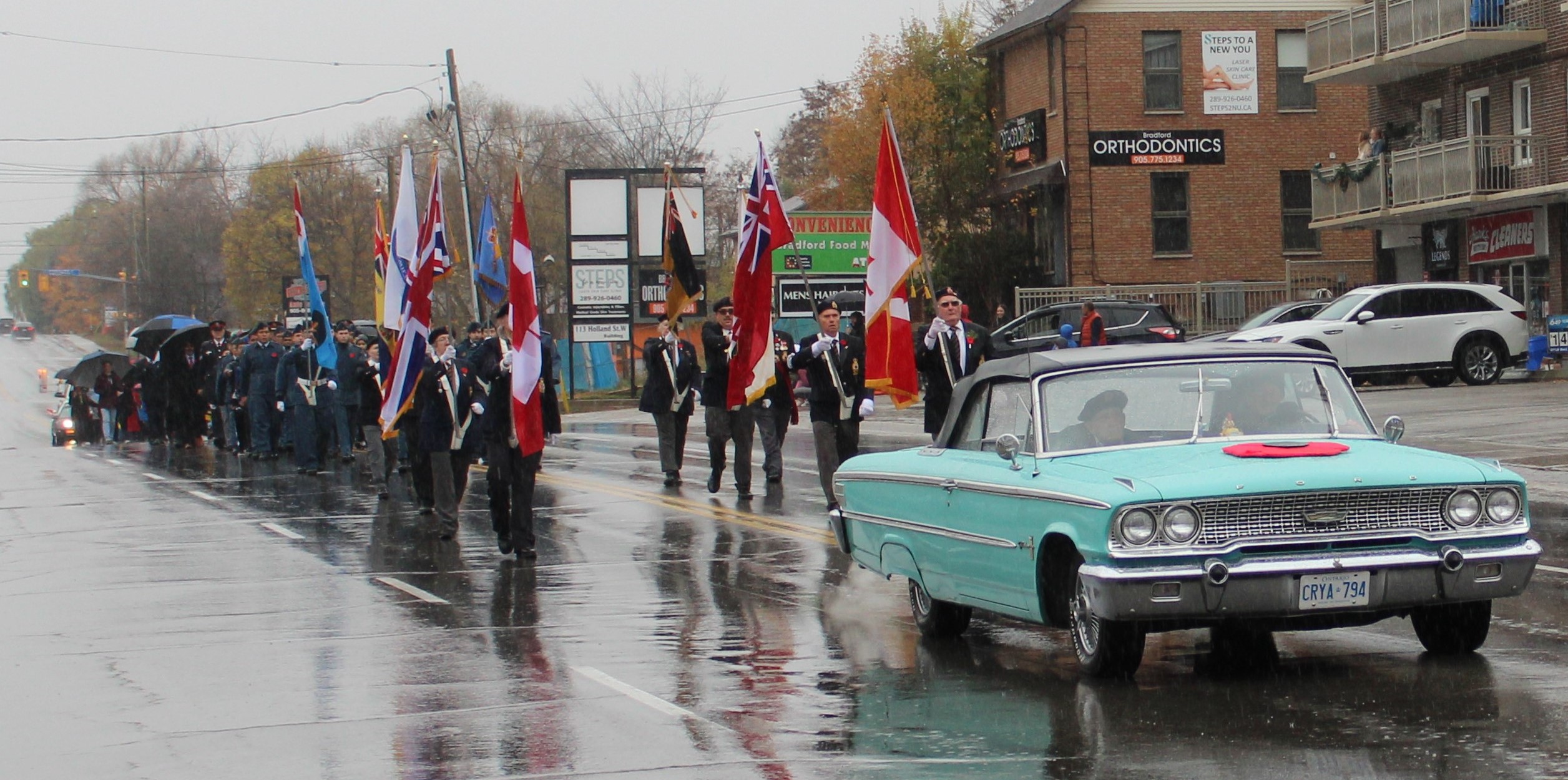 remembrance day parade individuals walking behind the a car