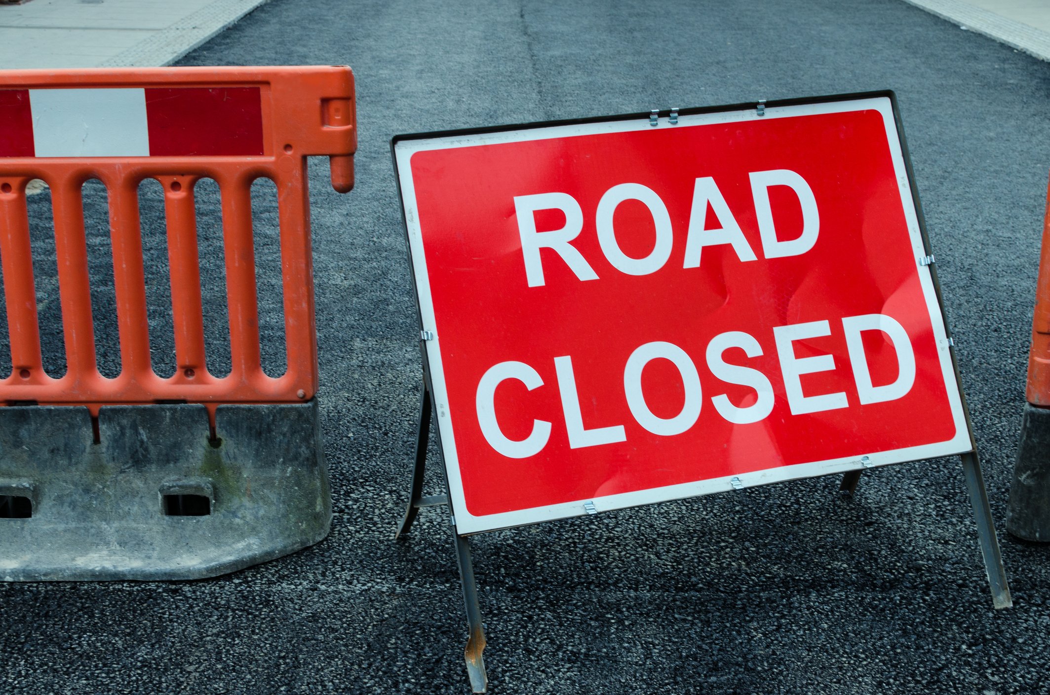 Sign and barricade on roadway; sign reads "Road Closed"