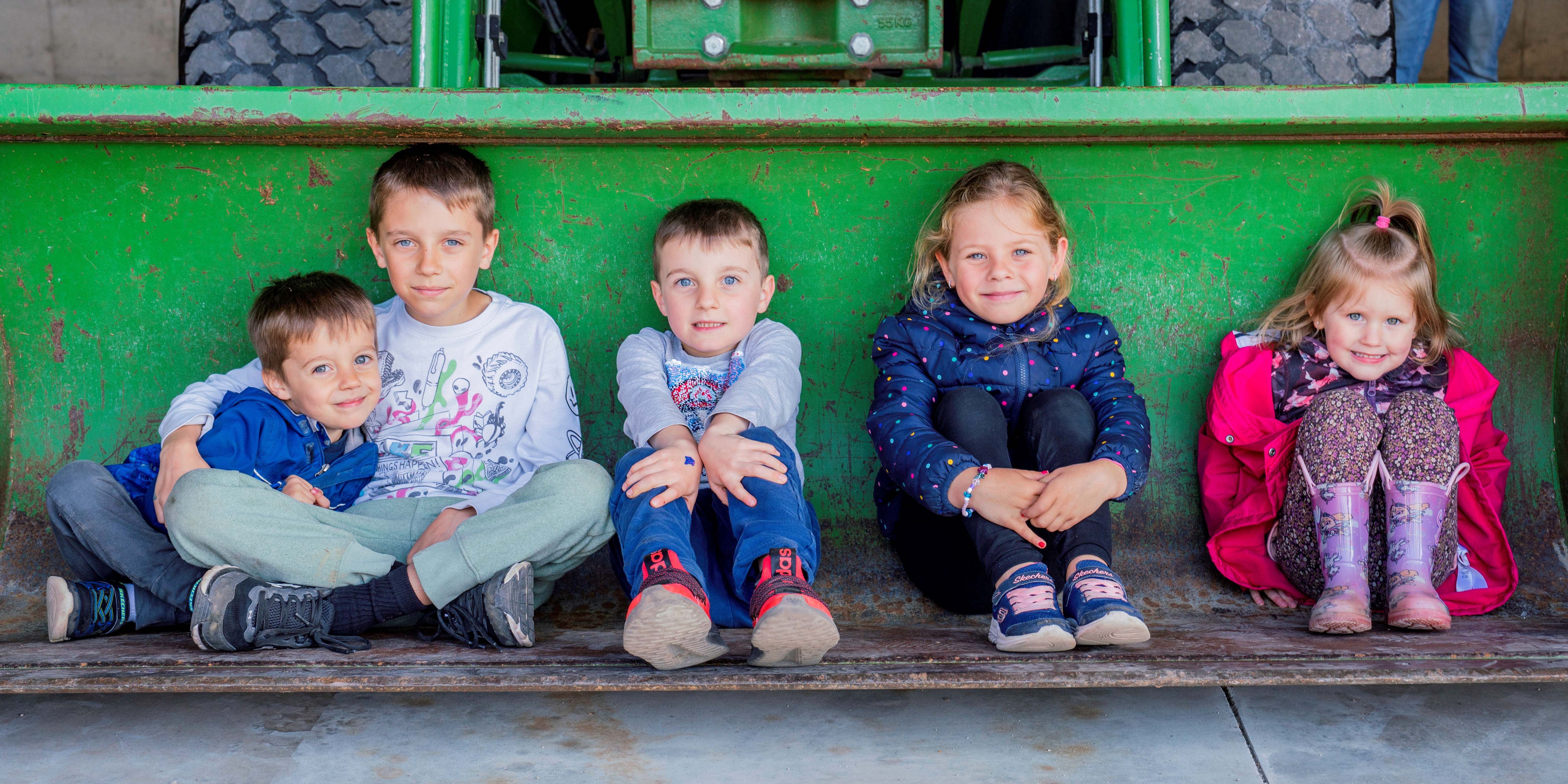 children sitting in the front loader of a truck