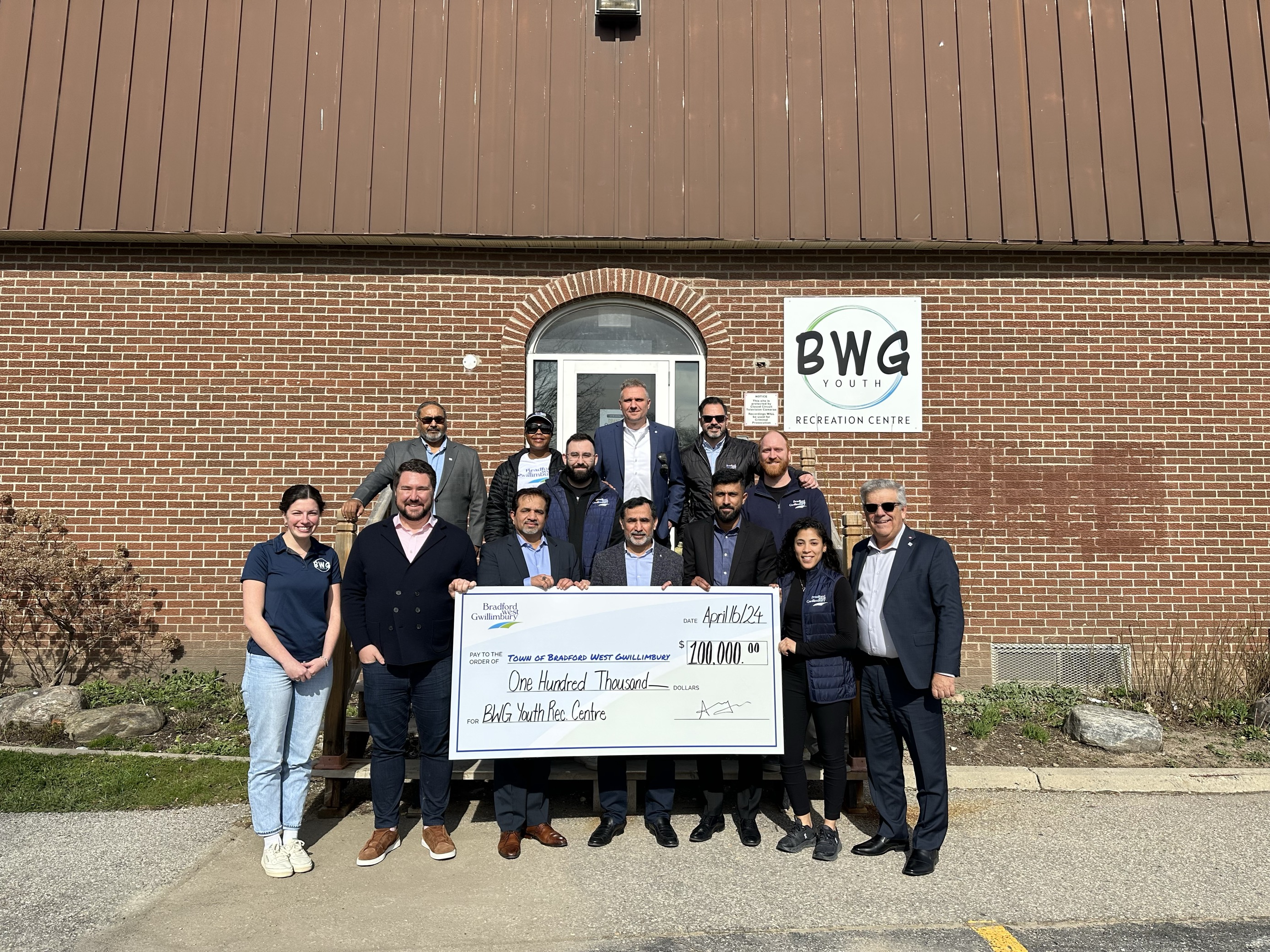 Council, BWG Employees, and Ayaz Ahmed and his business parteners holding up a $100,000 donation cheque outside of the Youth Recreation Centre