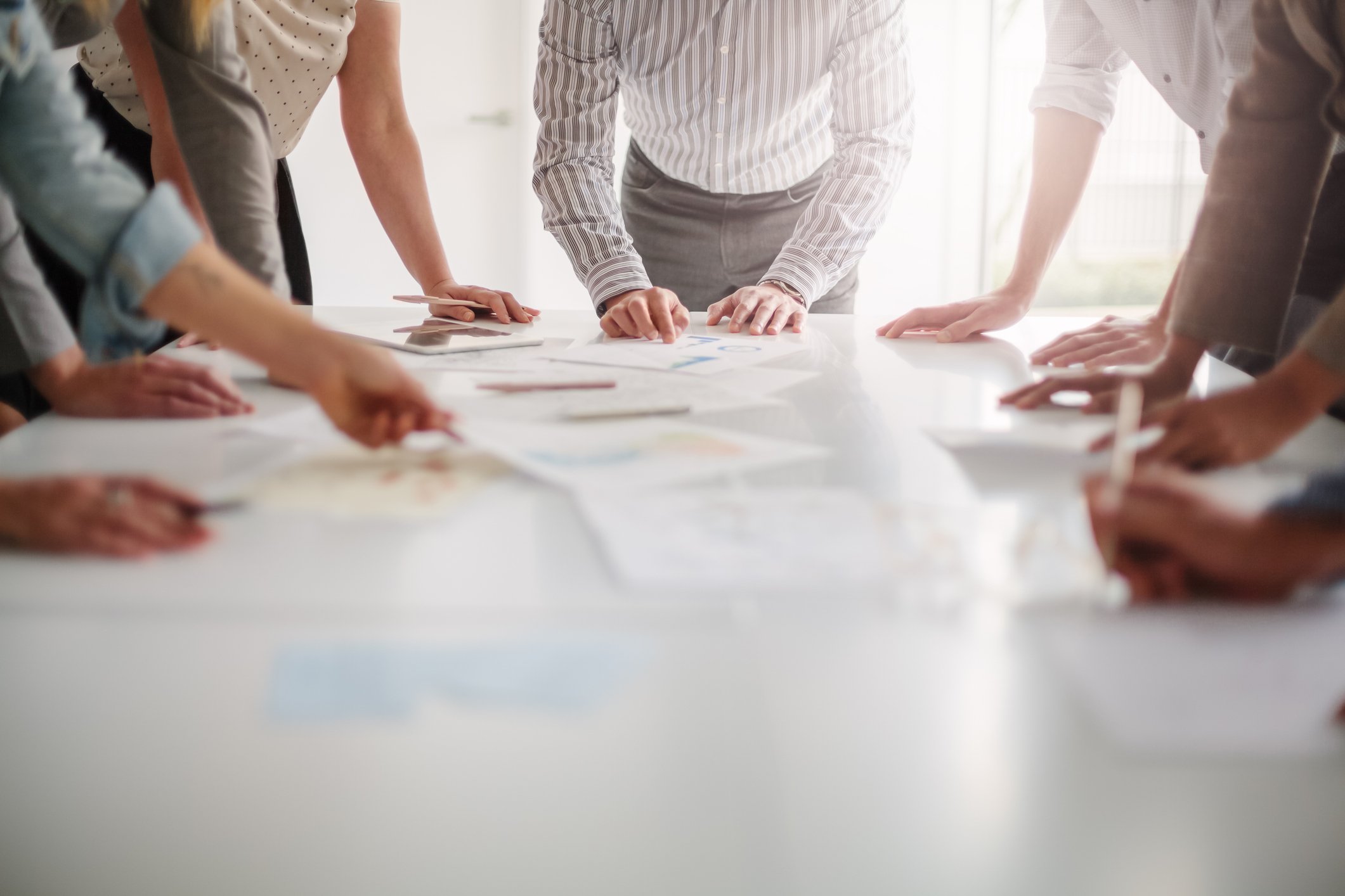 Group of people brainstorming together with documents on table