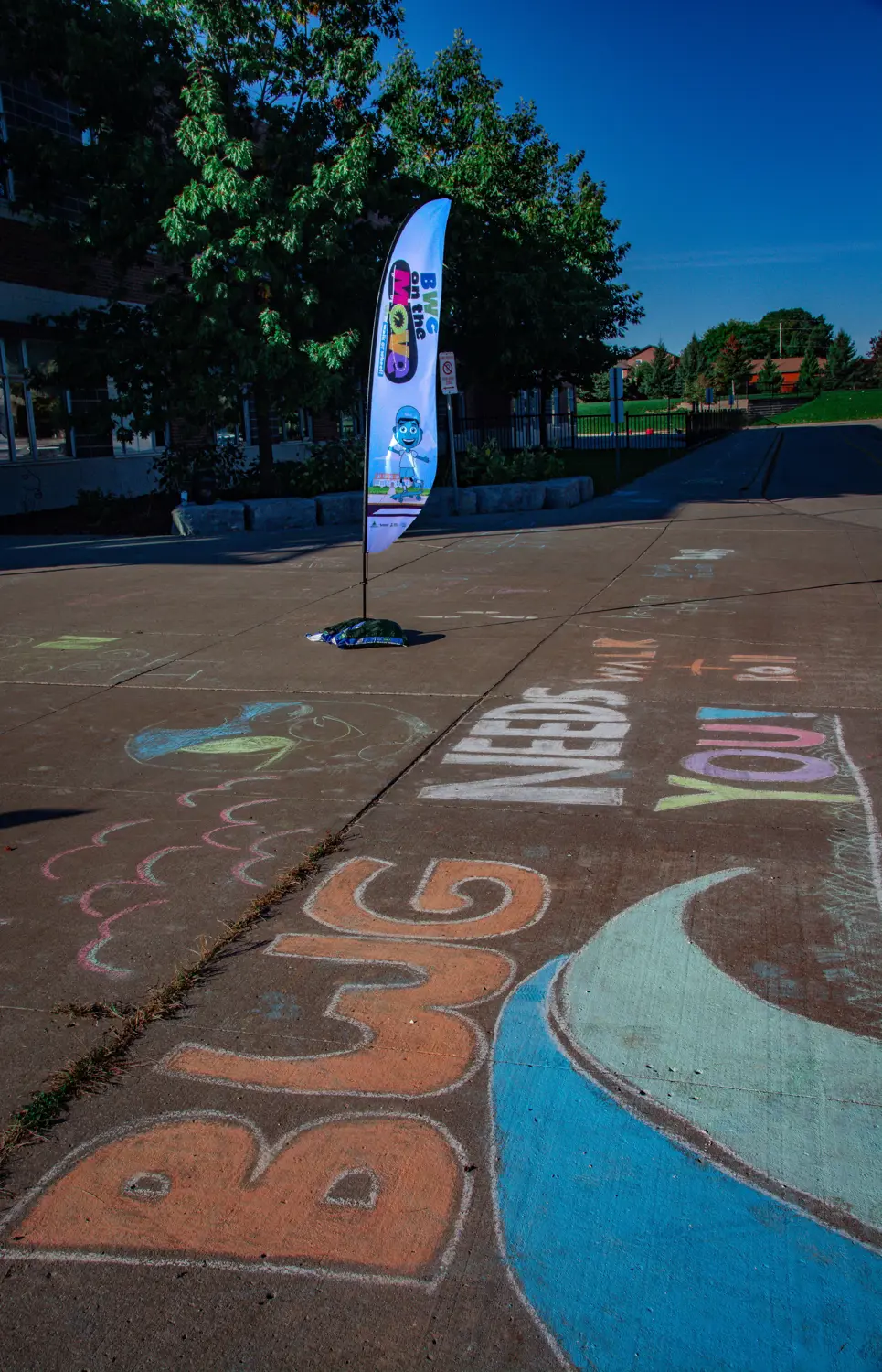 Sail flag with on the move logo on pavement with sidewalk chalk wrtiting