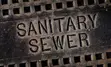 Sanitary sewer man hole cover iron lid reading "Sanitary Sewer"