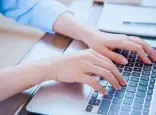 Hands typing on a computer keyboard.