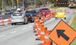 A standard move left sign and a digital flashing arrow with traffic cones advises all traffic to move into the left lane.