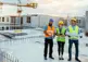 Employees working on construction site, wearing protective equipment and discussing the project